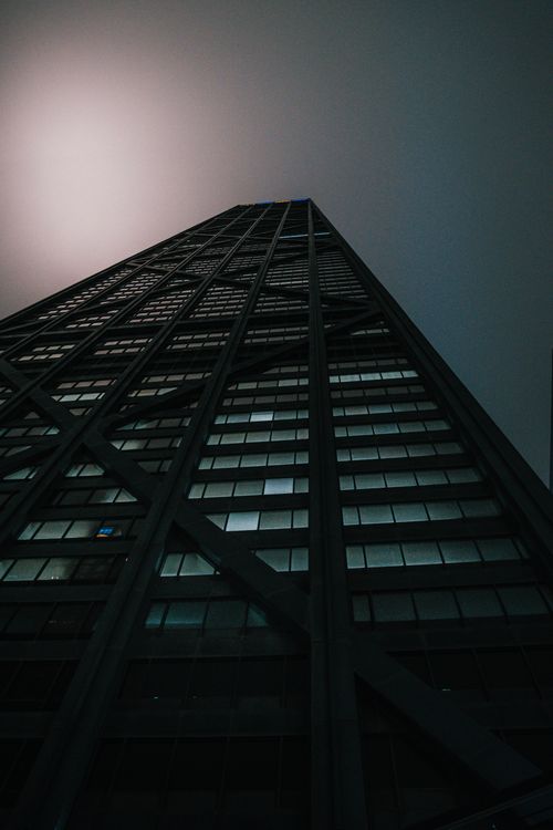 Free An illuminated skyscraper photographed from below at night, highlighting its striking facade and urban setting. Stock Photo