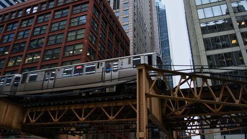 Free A city train moves on elevated tracks amidst towering urban buildings. Stock Photo
