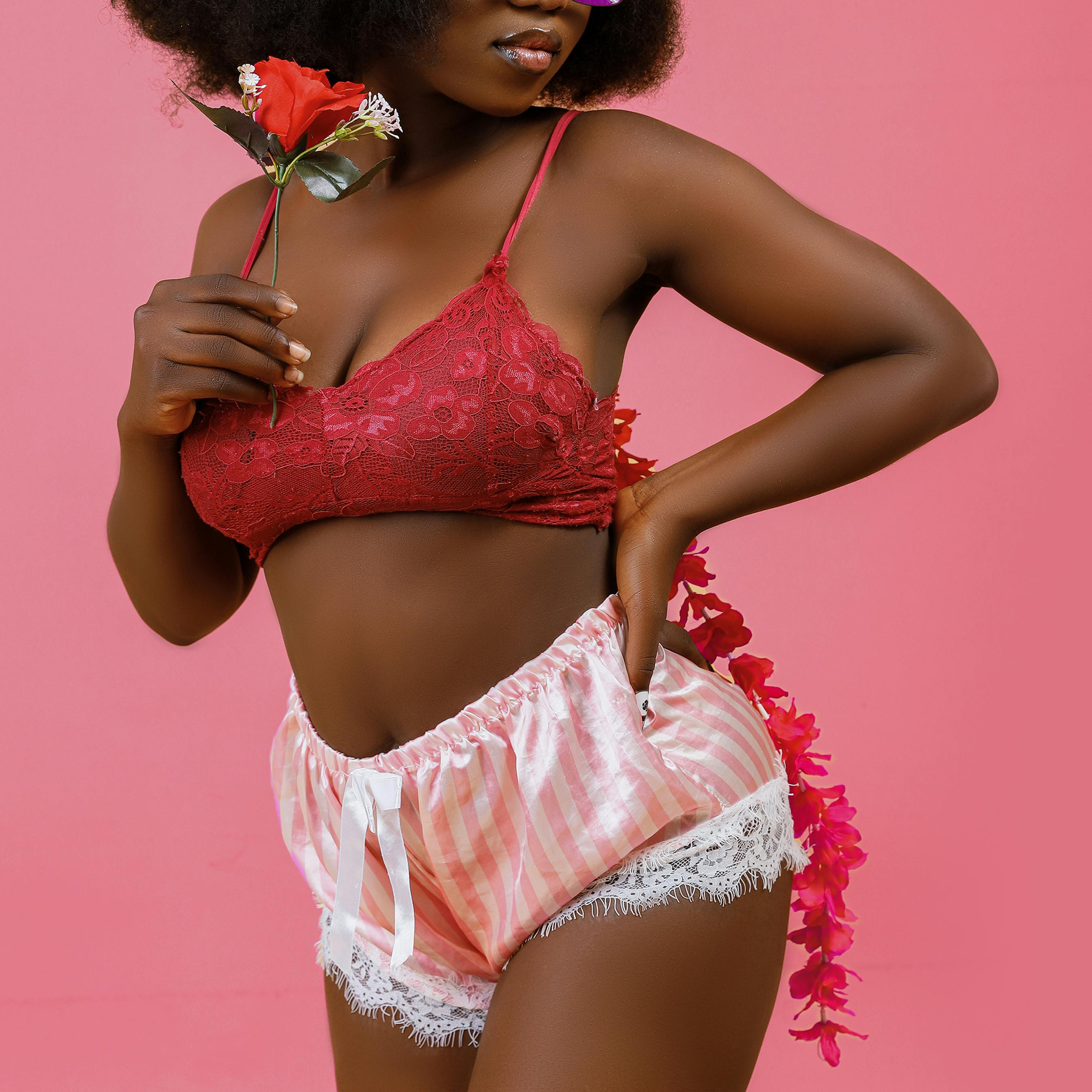 Free Chic lingerie fashion model posing with flower in hand, exuding elegance and style. Stock Photo