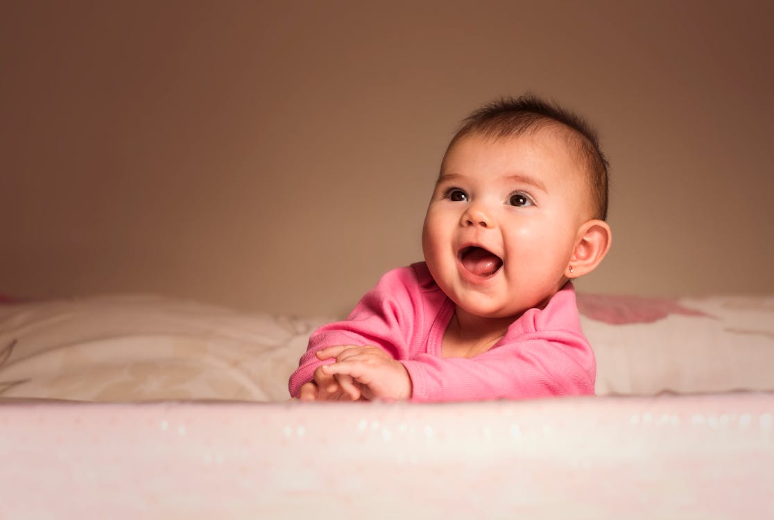 Free Smiling Baby Lying on Bed in Room Stock Photo