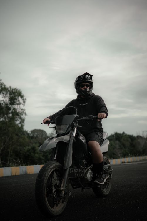 Free A man in helmet riding a motorbike on a cloudy day, showcasing adventure. Stock Photo