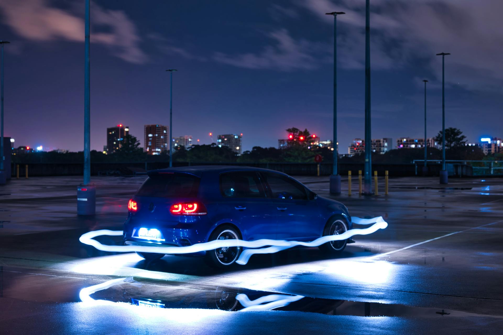 A vibrant urban night scene in Sydney featuring a car with light trails.