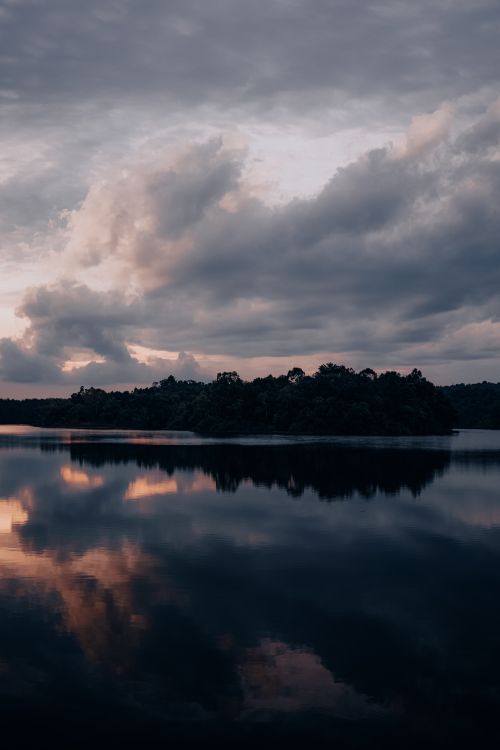 Free Tranquil lake scene at dusk with dramatic cloud reflections on the water surface. Stock Photo