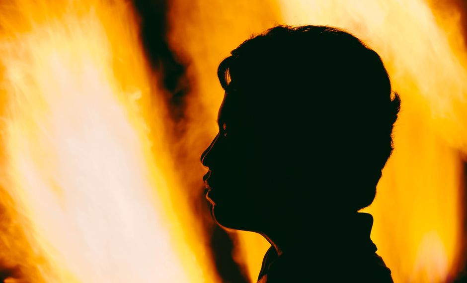 Como Cultivar a Resiliência Emocional no Dia a Dia 2 A dramatic silhouette of a person's profile against vivid orange flames.