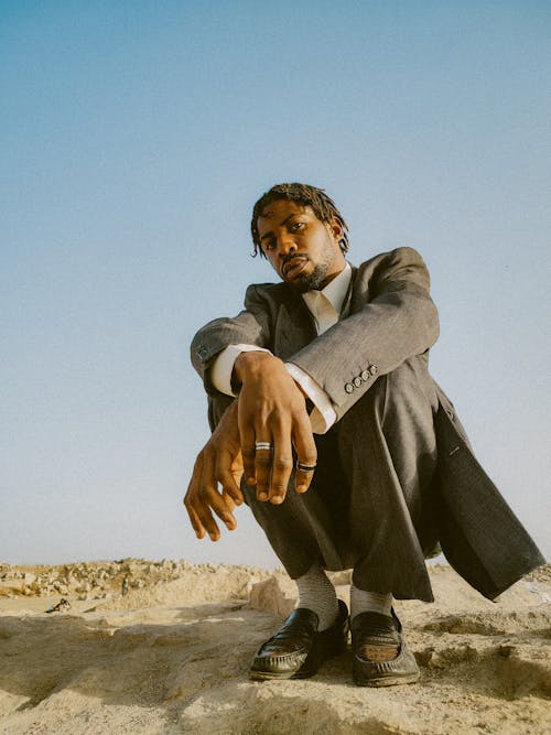 Man in Full Suit Crouching on Desert