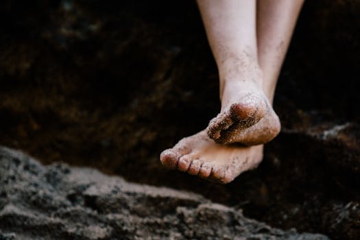 Close-up of sandy barefoot legs relaxing on a Malibu beach, capturing leisure and tranquility.
