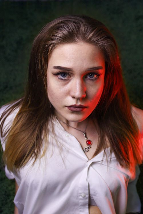 Free Captivating portrait of a woman looking up, featuring red dramatic lighting against a dark background. Stock Photo