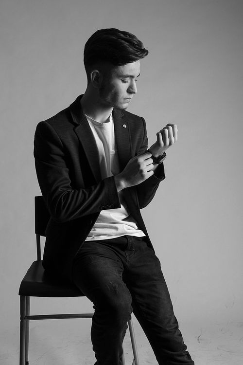 Free Elegant black and white portrait of a man posing in a suit, sitting on a chair. Stock Photo
