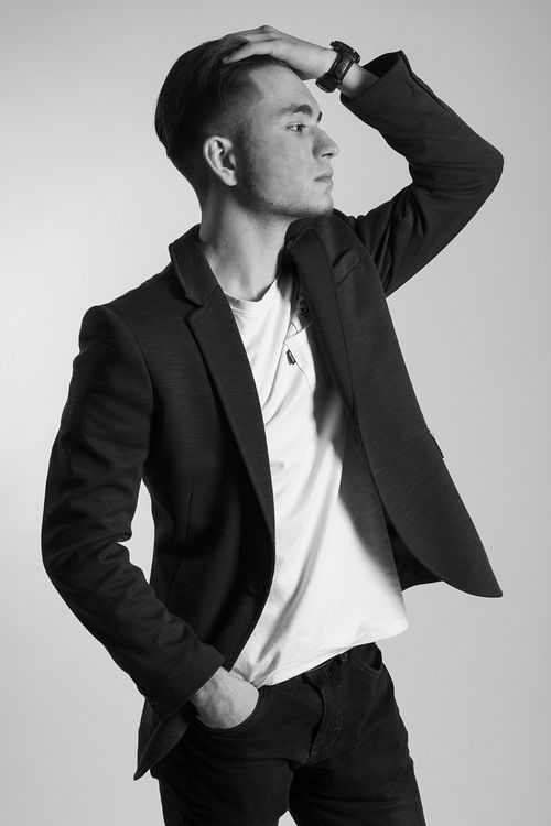 Free Black and white portrait of a stylish man wearing a suit, posing thoughtfully with hand on head. Stock Photo