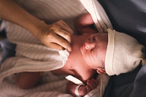 Free Person Covering Infant With Swaddling Blanket  Stock Photo