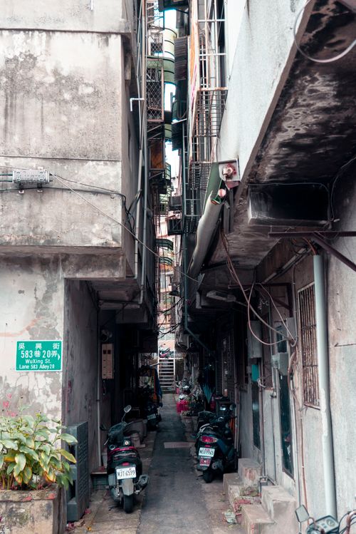 Free A narrow alleyway in a city with motor scooters parked alongside the walls. Stock Photo