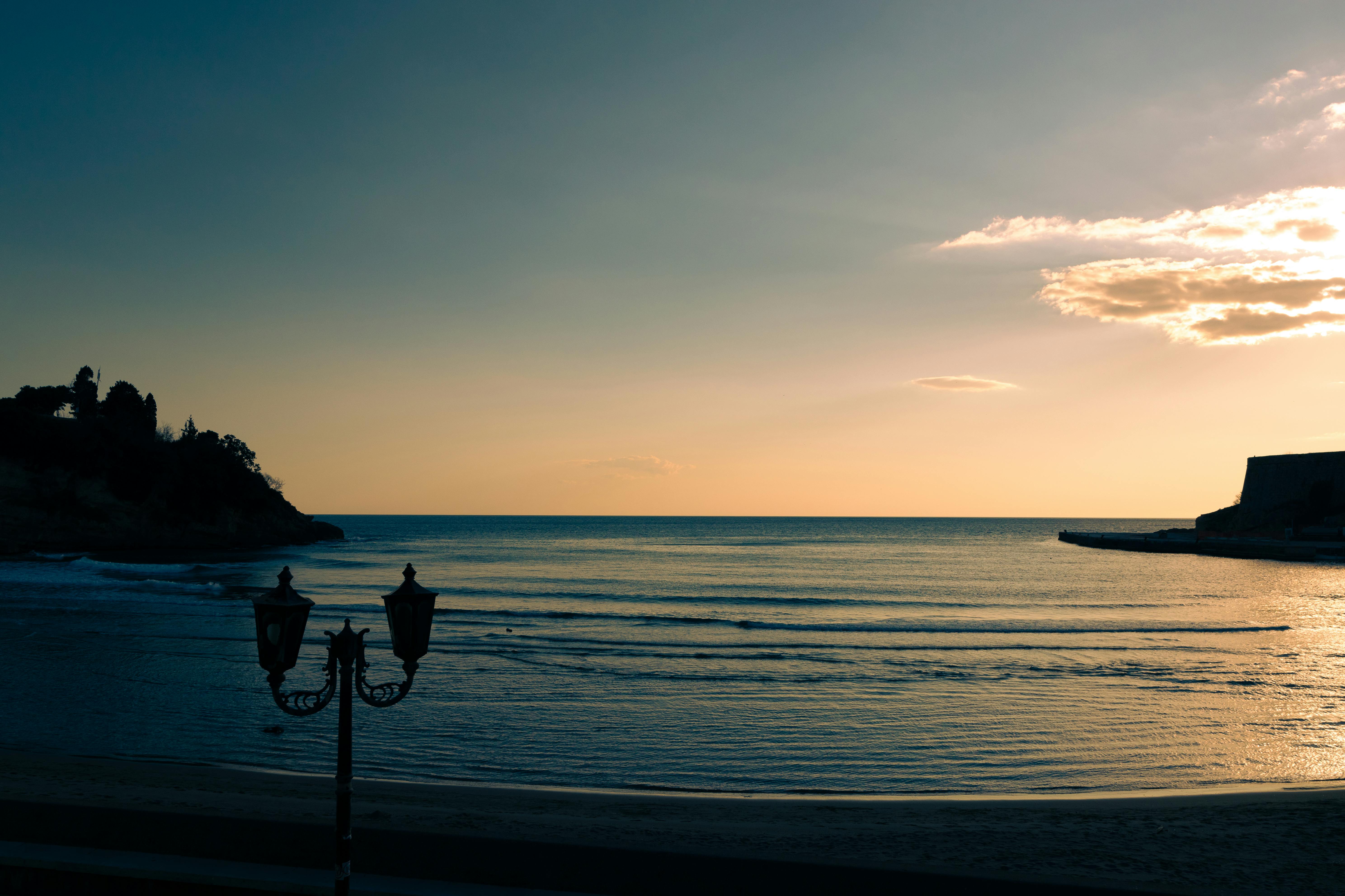 Serene beach at sunset in Ulcinj, Montenegro, with calm waves and vibrant skies.
