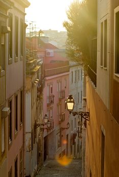 Discover a quaint alleyway in Lisbon, Portugal, bathed in warm sunset light, showcasing classic architecture.