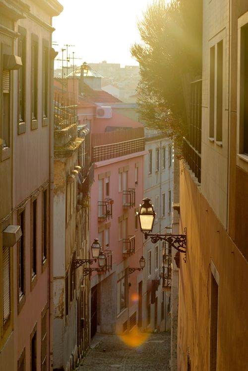 Free Discover a quaint alleyway in Lisbon, Portugal, bathed in warm sunset light, showcasing classic architecture. Stock Photo