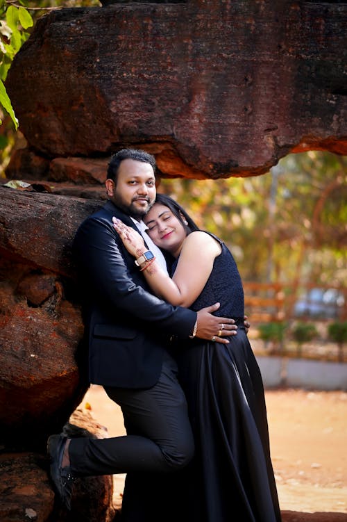Couple in Dress and Suit Hugging by Rocks