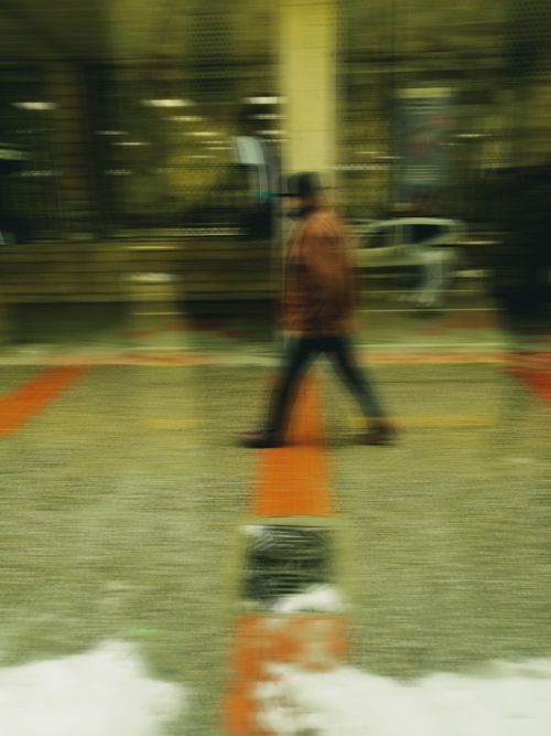 Free Blurred image of a person walking on a pavement in an urban environment, creating a dynamic feel. Stock Photo