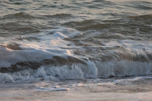 Free Close-up of ocean waves crashing on sandy shore with foamy water during the day. Stock Photo