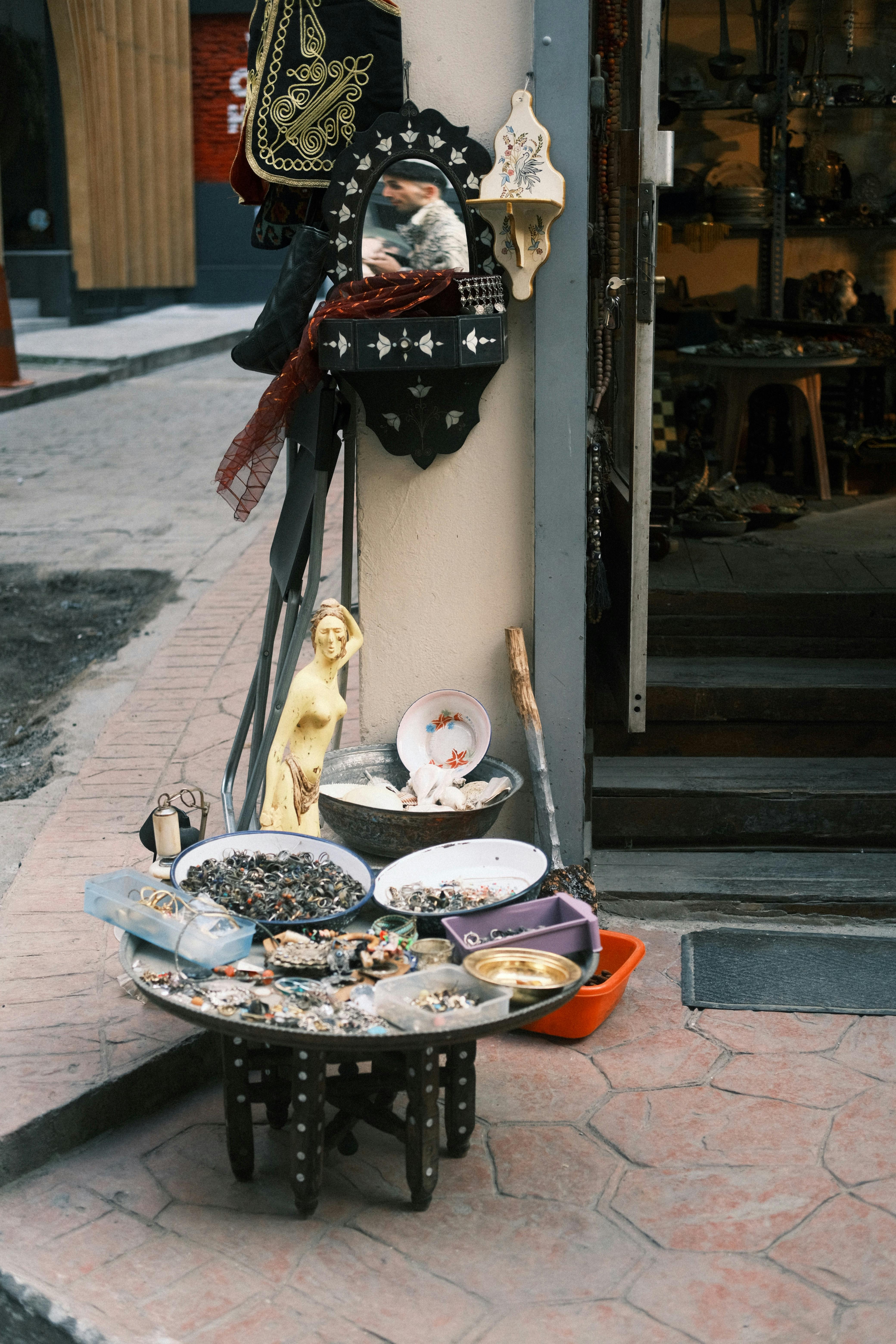 Free A captivating display of antiques and trinkets outside a quaint city shop, evoking traditional charm. Stock Photo