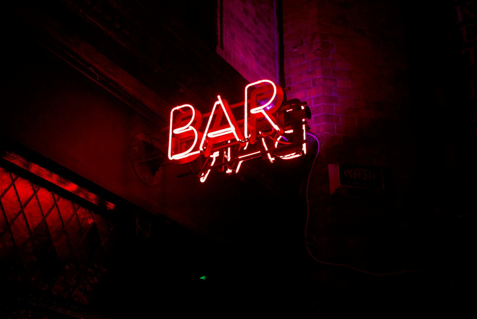 Vibrant red neon bar sign glowing in the night on a Dublin city street.