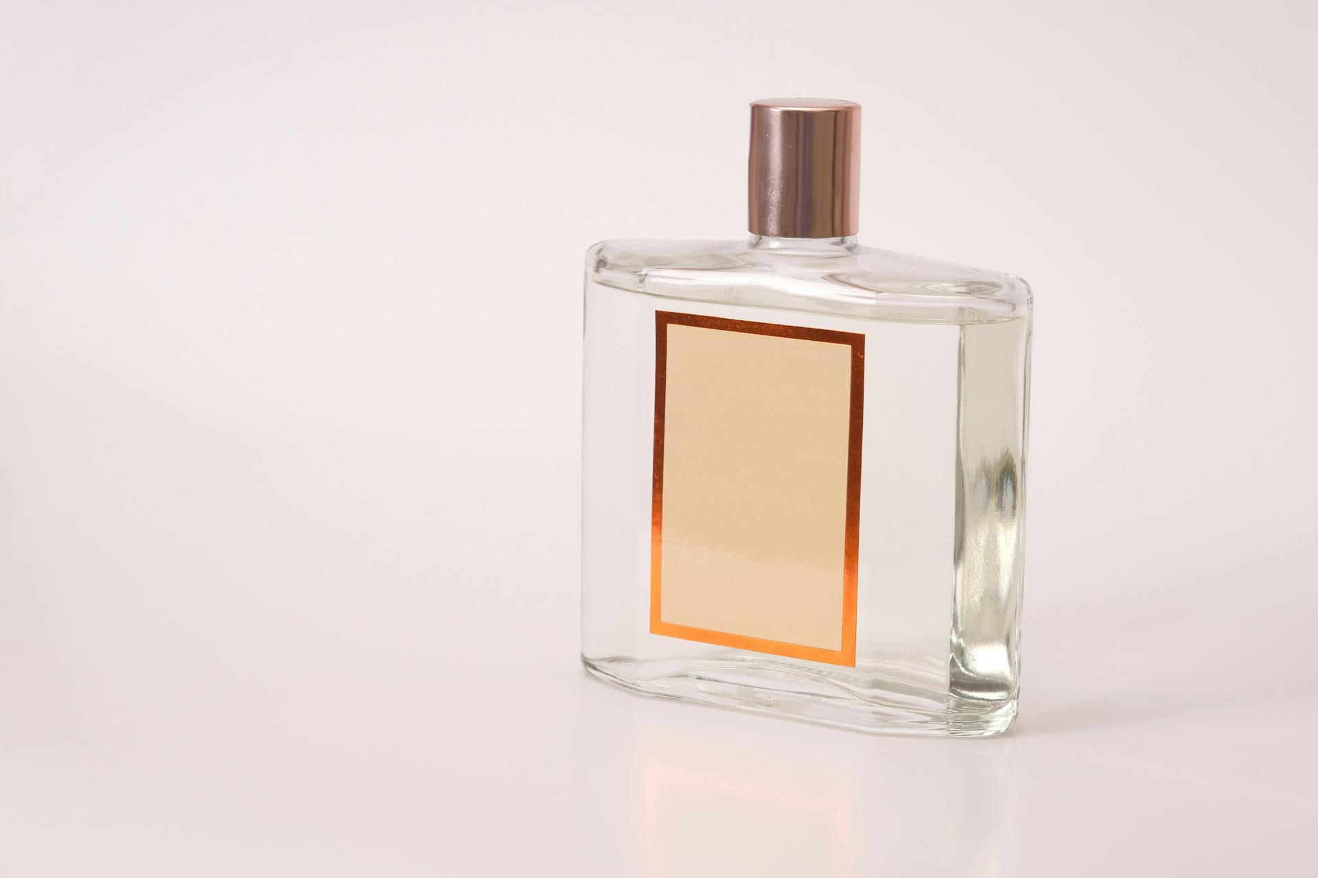 A clear perfume bottle with an empty label, suitable for branding or design purposes.