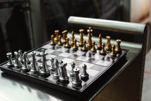 Free Elegant chessboard with gold and silver pieces, showcasing a polished modern design. Stock Photo