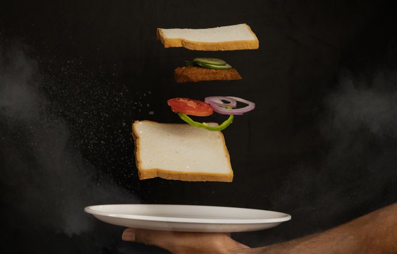 Deconstructed sandwich with floating ingredients on a dark backdrop — photo by rajan vijayakumar on Pexels