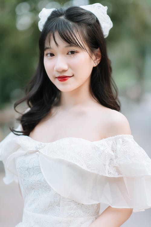 Portrait of a Brunette Girl Wearing a White Dress with Decollete and a Hair Bow