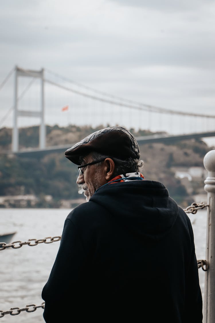 Back View Of A Senior Man Wearing A Flat Cap Standing By A River