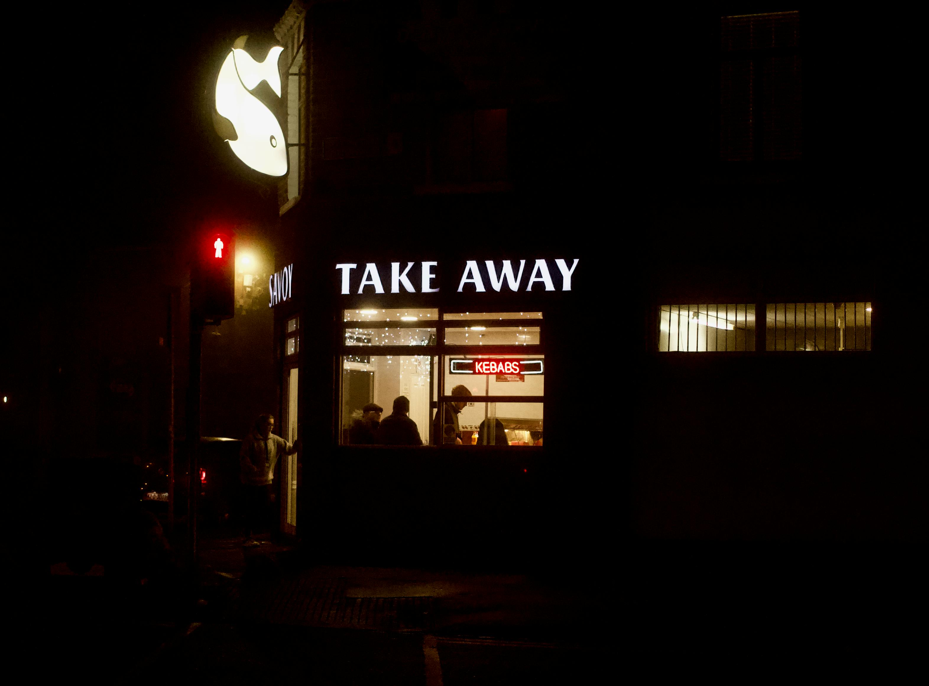 Gratis Vista notturna di un negozio di cibo da asporto a Dublino, Irlanda, con insegna illuminata e persone all'interno. Foto a disposizione
