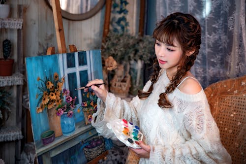 Young Woman Holding a Palette and Painting on Canvas 