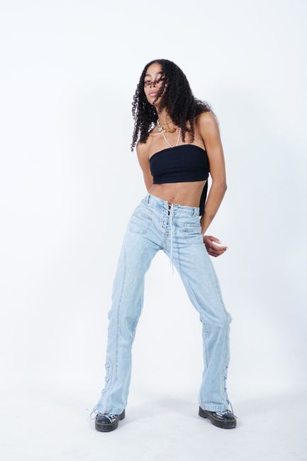 Fashion model with long curly hair posing in casual outfit against white background, showcasing modern style.