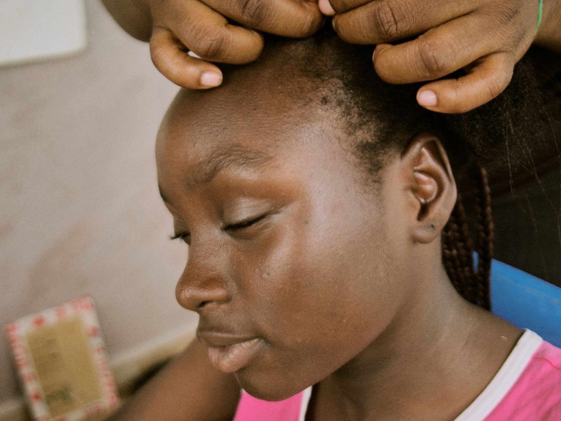 African woman having her hair braided carefully