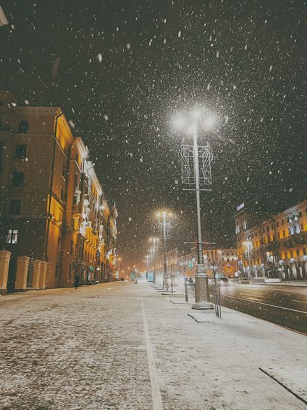 Snow falling on a lamplit street at night, photo by Julia C on Pexels