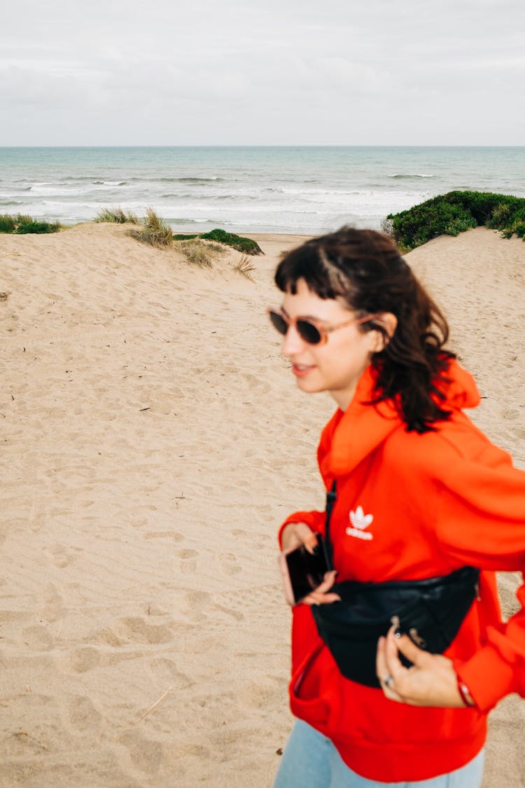 Young Woman In A Hoodie Walking On The Beach 