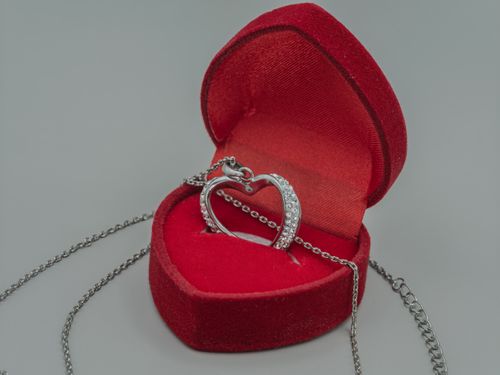 Free A heart-shaped diamond pendant in a red velvet box signifies love and elegance. Stock Photo