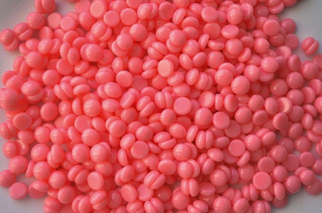 Billes de cire rose utilisées pour l'épilation en institut