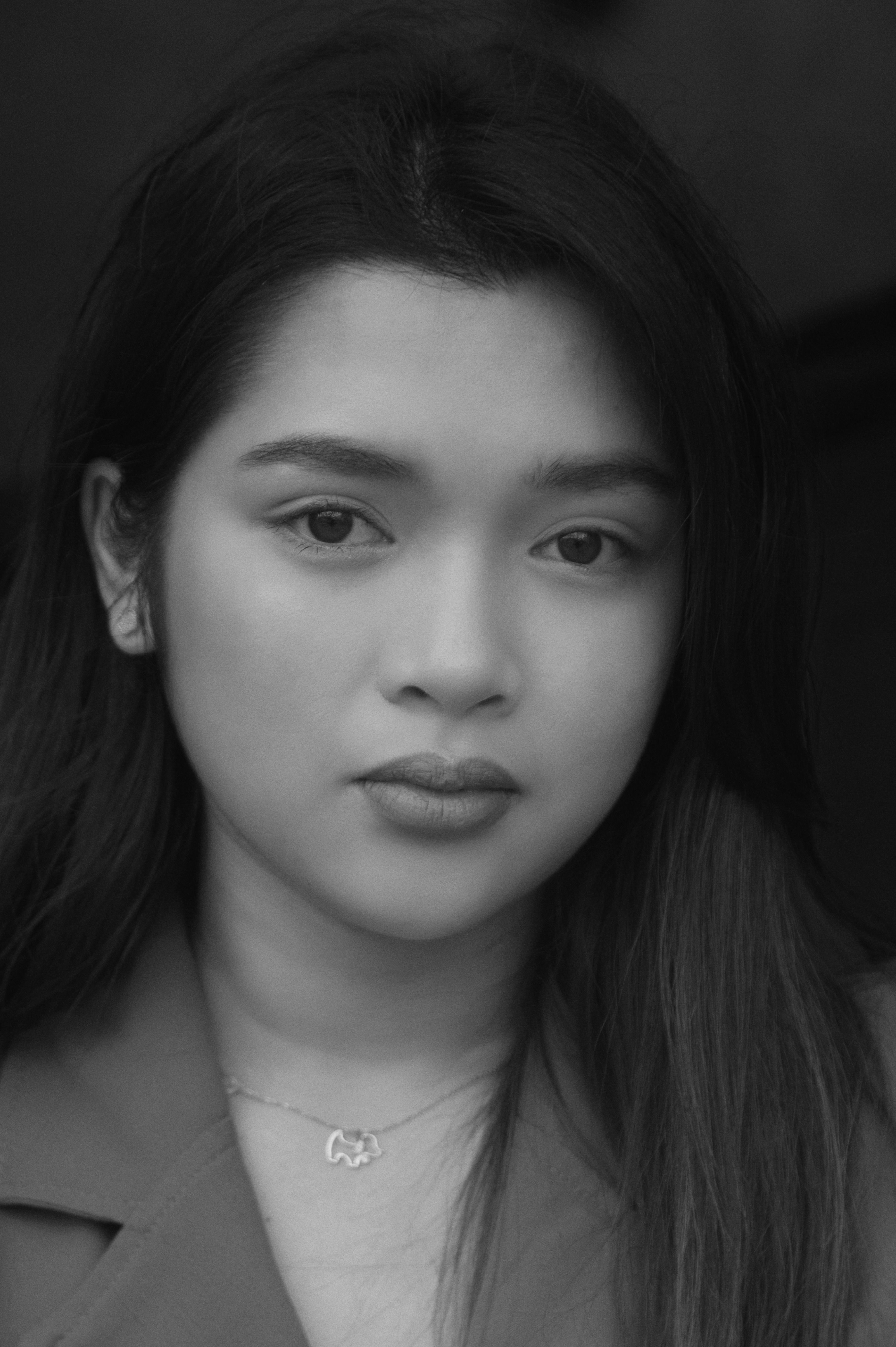 Close-up black and white portrait of a young woman with a serene expression.