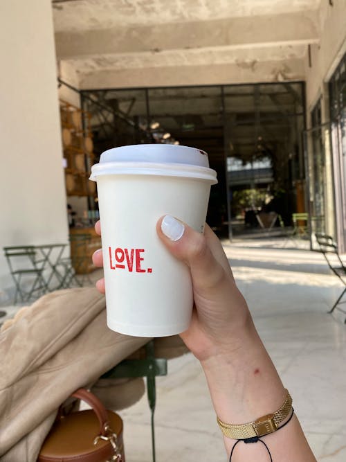 Holding a Disposable Cup with Love Printed on It