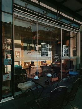 Charming outdoor café seating with glass facade and visible urban scenery.