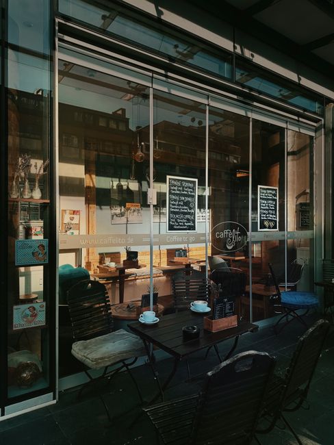 Charming outdoor café seating with glass facade and visible urban scenery.