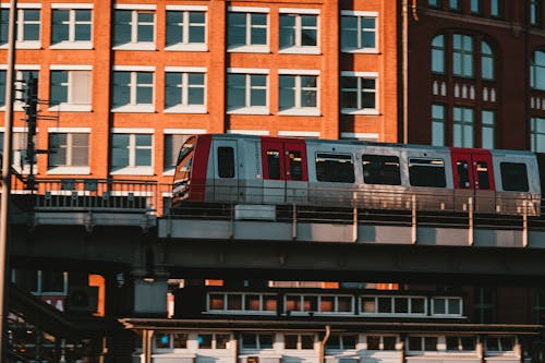 免費 棕色混凝土建築附近的白色和紅色火車 圖庫相片