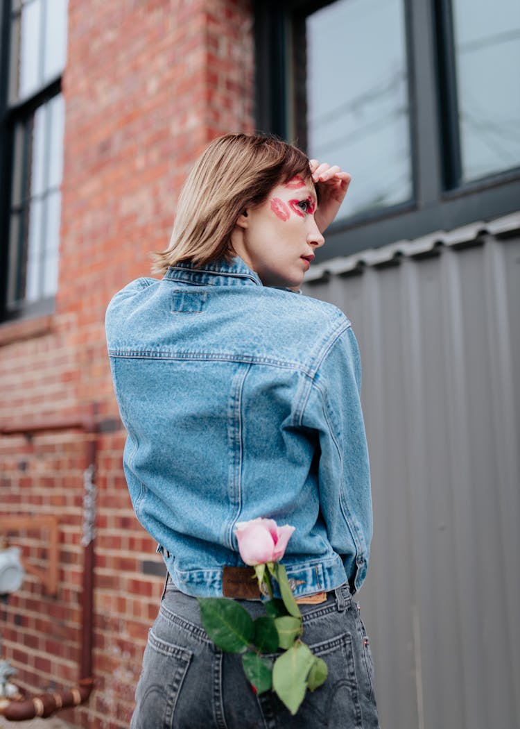 Young Woman With A Pink Rose In The Back Pocket And Traces Of Lipstick On Her Face