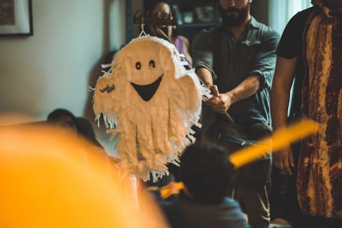 Free Person Holding Stick in Front of White Ghost Pinata Stock Photo