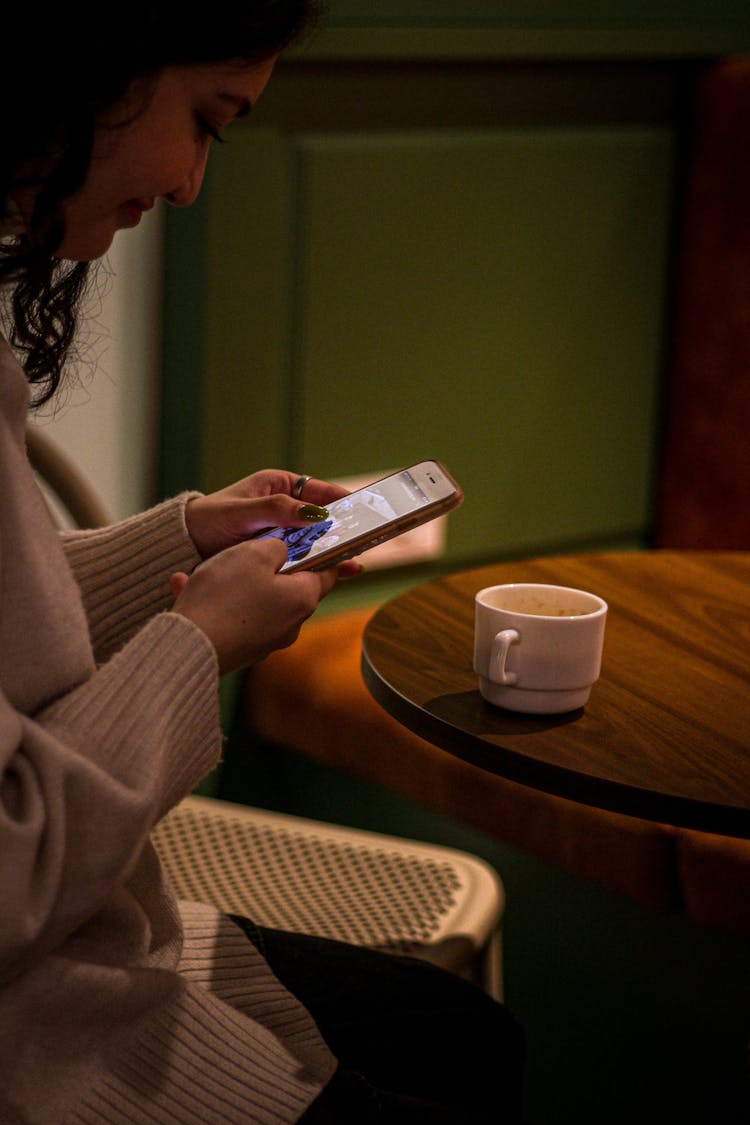 Woman Sitting With Smartphone By Table