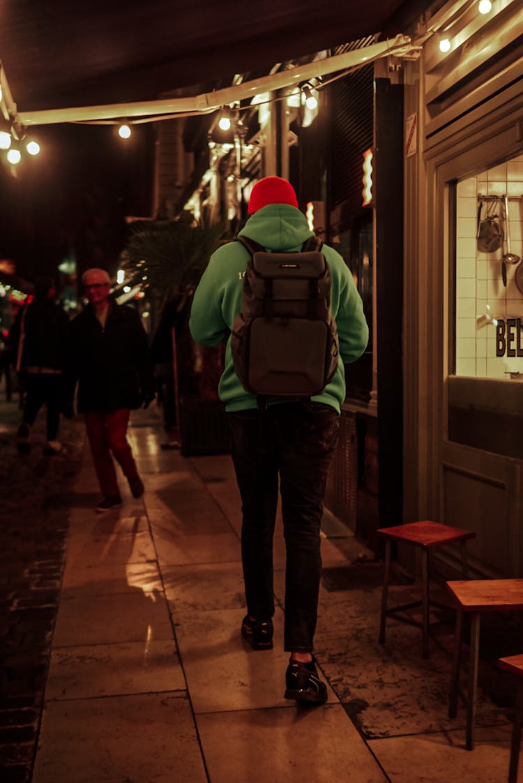 Man With Black Backpack Walking On Sidewalk At Night