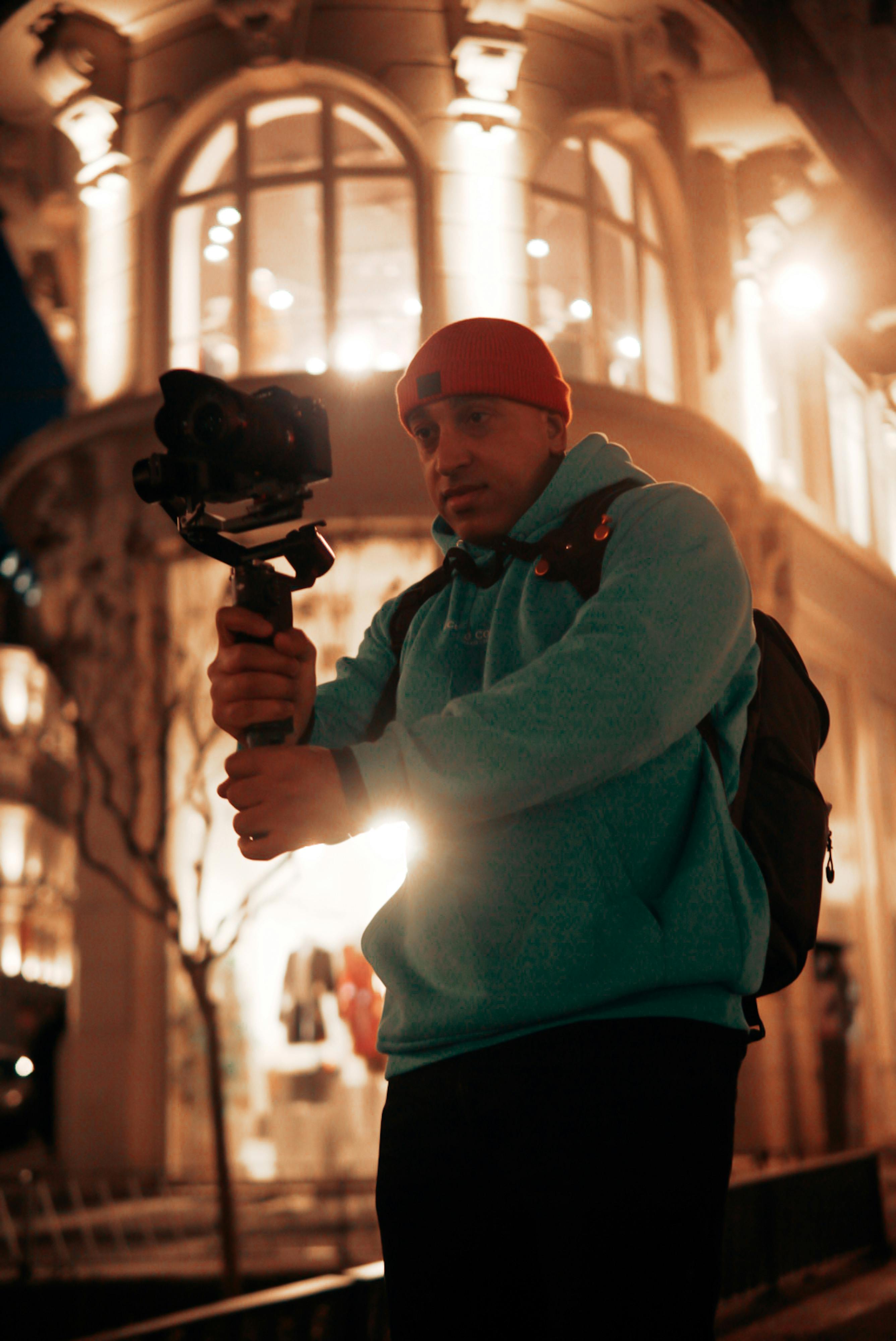 man with a camera on a gimbal filming in the street at night