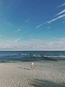 A serene beach scene featuring an expansive blue sky, calm sea, and sandy shore under a clear summer day.