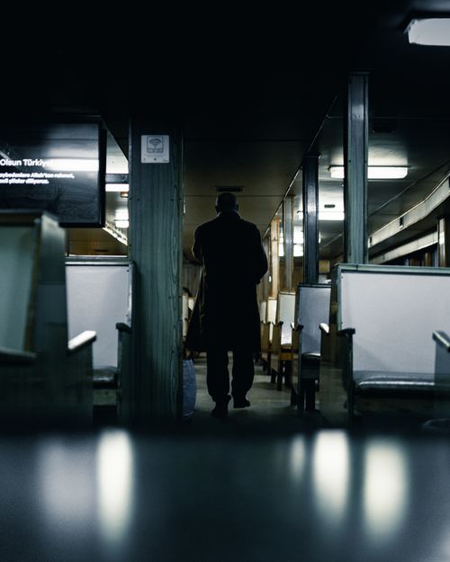 Free Silhouette of a man walking through an empty, dimly lit train interior, adding suspense. Stock Photo