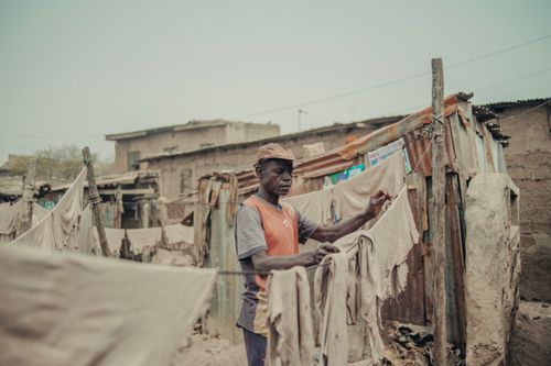 Free A man handling laundry outdoors in a rustic setting. Daily chores depicted in a natural, candid moment. Stock Photo