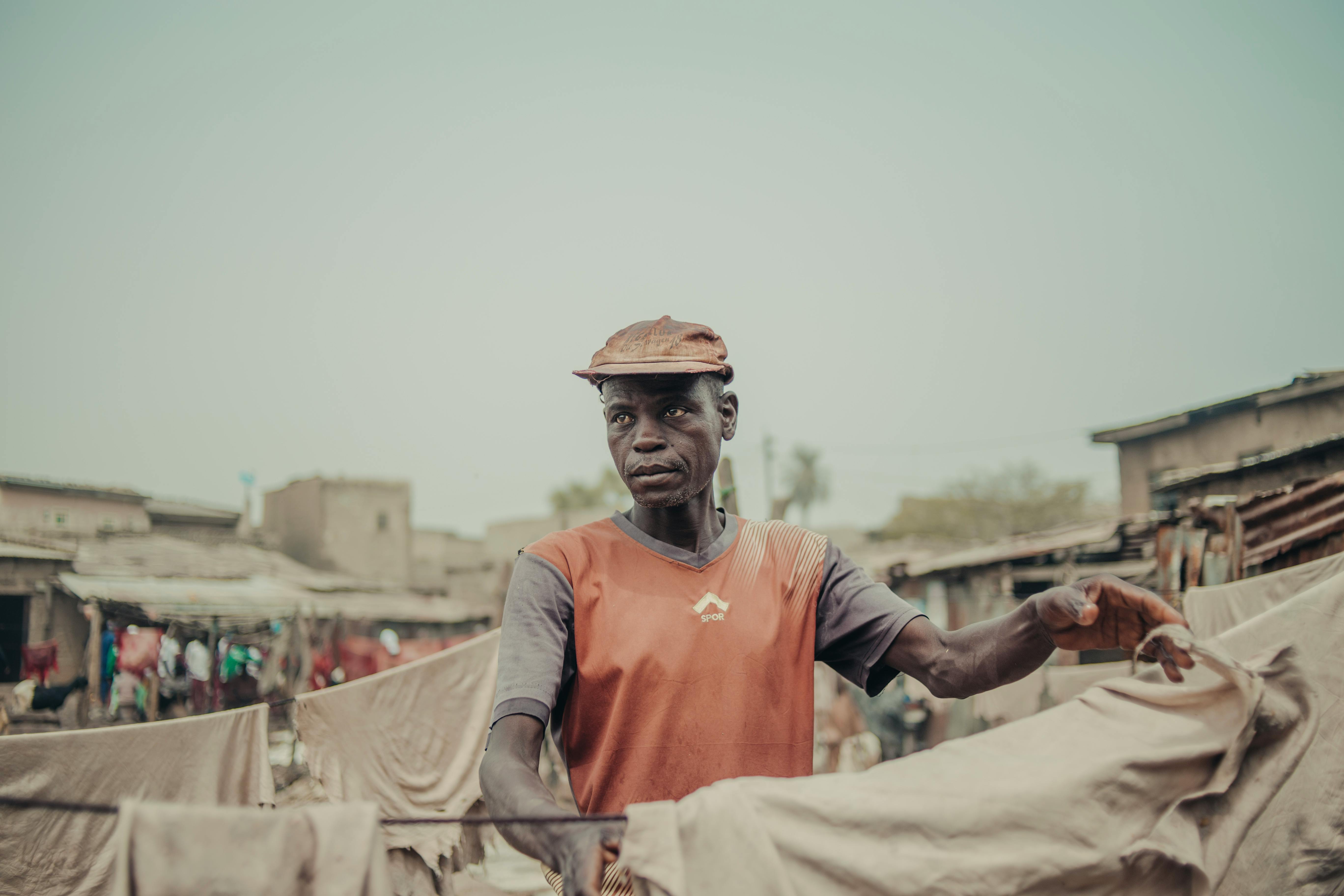A man drying clothes outdoors in a rural area, depicting a daily chore routine.